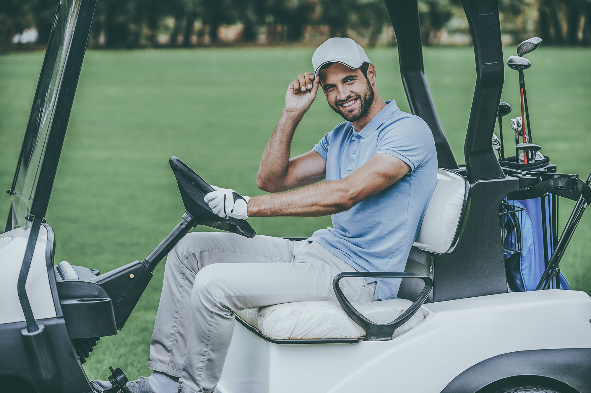 Man in golf cart. Side view of handsome young man driving a golf